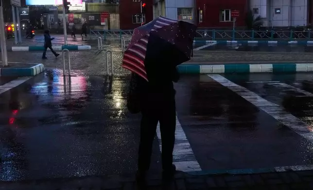 A man with an umbrella crosses a street in Tehran, Iran, Wednesday, Dec. 10, 2025. (AP Photo/Vahid Salemi)