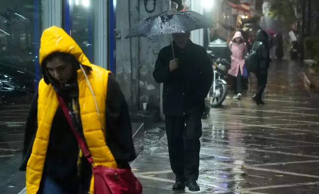 A man walks with an umbrella under a rain in Tehran, Iran, Wednesday, Dec. 10, 2025. (AP Photo/Vahid Salemi)