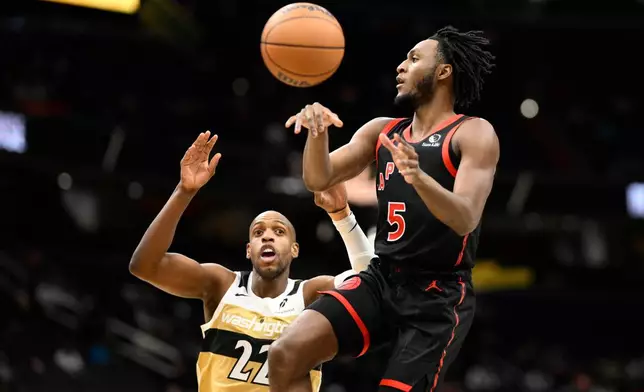 Toronto Raptors guard Immanuel Quickley (5) passes the ball against Washington Wizards forward Khris Middleton (22) during the first half of an NBA basketball game, Friday, Dec. 26, 2025, in Washington. (AP Photo/Nick Wass)