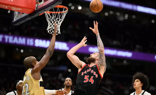 Toronto Raptors forward Sandro Mamukelashvili (54) shoots against Washington Wizards forward Khris Middleton (22) during the first half of an NBA basketball game, Friday, Dec. 26, 2025, in Washington. (AP Photo/Nick Wass)