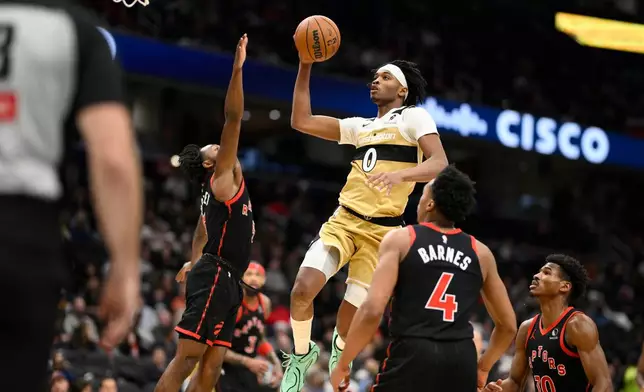 Washington Wizards guard Bilal Coulibaly (0) goes to the basket against Toronto Raptors forward Scottie Barnes (4), guard Ochai Agbaji (30) and guard Immanuel Quickley, left, during the second half of an NBA basketball game, Friday, Dec. 26, 2025, in Washington. (AP Photo/Nick Wass)