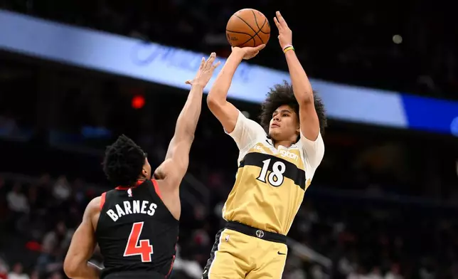 Washington Wizards forward Kyshawn George (18) goes up to shoot against Toronto Raptors forward Scottie Barnes (4) during the second half of an NBA basketball game, Friday, Dec. 26, 2025, in Washington. (AP Photo/Nick Wass)