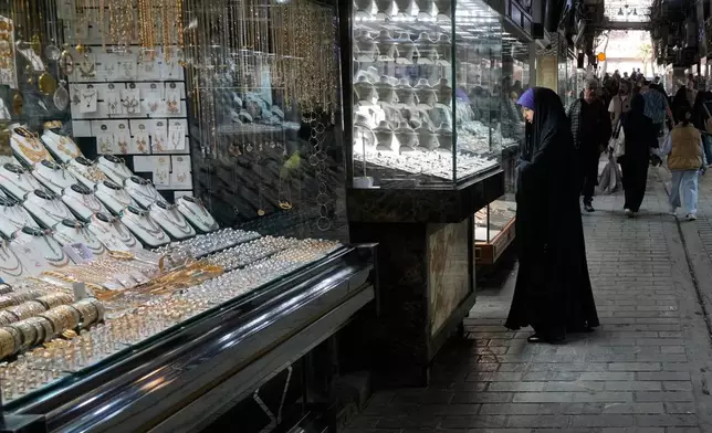 A woman looks at the window of a gold shop at a gold market in Tehran's Grand Bazaar, Iran, Saturday, Nov. 29, 2025. (AP Photo/Vahid Salemi)