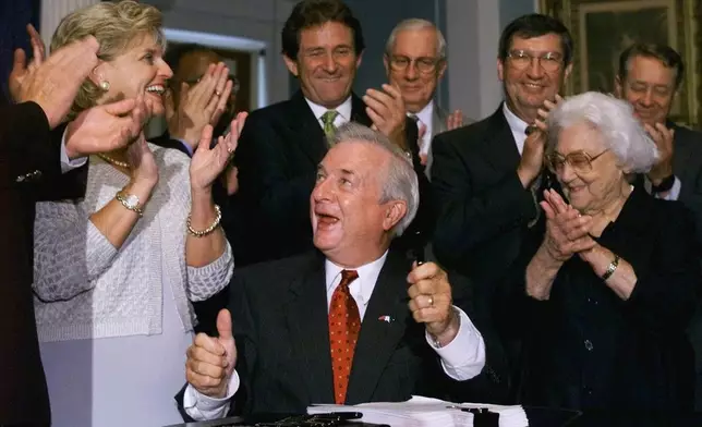FILE - North Carolina Gov. Jim Hunt, center, gives the thumbs up to House and Senate leadership after signing the 1999-2001 state budget during a ceremony at the Capitol building, in Raleigh, N.C., June 30, 1999. (AP Photo/Chuck Burton, File)