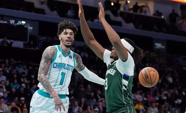 Charlotte Hornets guard Lamelo Ball passes around Milwaukee Bucks center Myles Turner during the first half of an NBA basketball game, Monday, Dec. 29, 2025, in Charlotte, N.C. (AP Photo/Chris Carlson)
