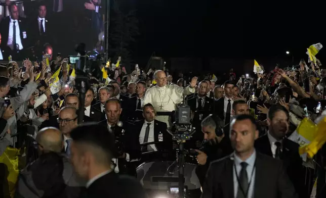 Pope Leo XIV greets the crowd as he arrives surrounded by security for a meeting with youths in Bkerki, the seat of the Maronite Church, in Lebanon, Monday, Dec. 1, 2025. (AP Photo/Bilal Hussein)