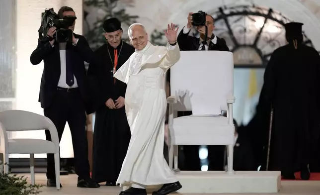 Pope Leo XIV greets the crowd as he arrives surrounded by security for a meeting with youths in Bkerki, the seat of the Maronite Church, in Lebanon, Monday, Dec. 1, 2025. (AP Photo/Bilal Hussein)