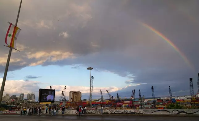 A rainbow rises behind the port and a billboard featuring Pope Leo XIV in Beirut, Lebanon, Tuesday, Dec. 2, 2025. (AP Photo/Hassan Ammar)