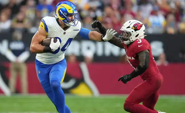 Los Angeles Rams tight end Colby Parkinson, left, avoids Arizona Cardinals safety Budda Baker after pulling in a pass in the first half of an NFL football game Sunday, Dec. 7, 2025, in Glendale, Ariz. (AP Photo/Ross D. Franklin)