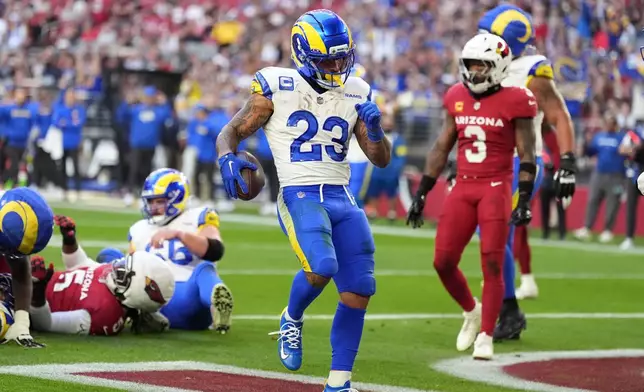 Los Angeles Rams running back Kyren Williams celebrates after running for a touchdown as Arizona Cardinals safety Budda Baker looks on in the first half of an NFL football game, Sunday, Dec. 7, 2025, in Glendale, Ariz. (AP Photo/Ross D. Franklin)