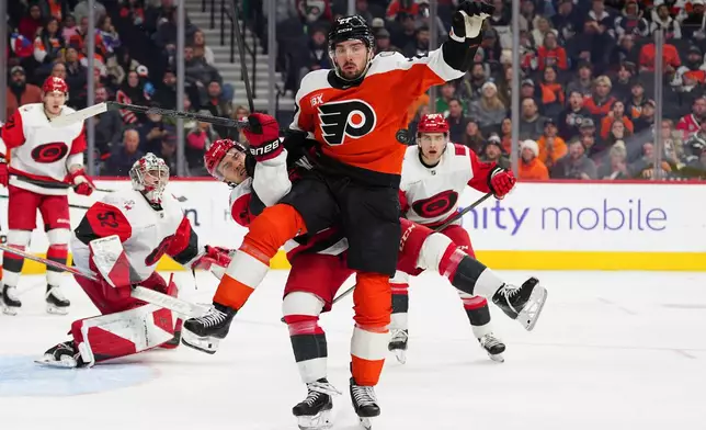 Philadelphia Flyers' Noah Cates, front, collides with Carolina Hurricanes' Logan Stankoven as they battle for the puck during the second period of an NHL hockey game, Saturday, Dec. 13, 2025, in Philadelphia. (AP Photo/Derik Hamilton)