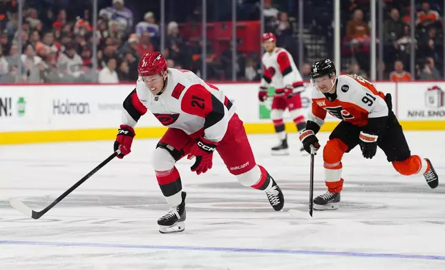 Carolina Hurricanes' Alexander Nikishin, left, gives chase for the puck past Philadelphia Flyers' Carl Grundstrom during the second period of an NHL hockey game, Saturday, Dec. 13, 2025, in Philadelphia. (AP Photo/Derik Hamilton)
