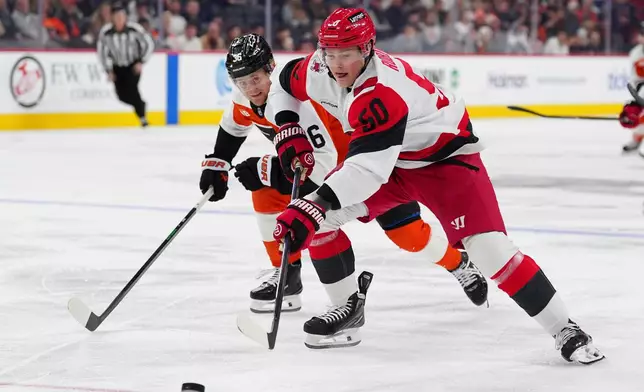 Carolina Hurricanes' Eric Robinson, right, battles for the puck against Philadelphia Flyers' Emil Andrae, left, during the first period of an NHL hockey game, Saturday, Dec. 13, 2025, in Philadelphia. (AP Photo/Derik Hamilton)