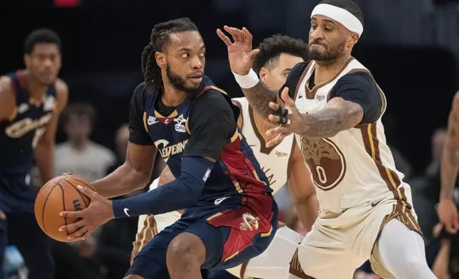 Cleveland Cavaliers' Darius Garland, left, keeps the ball from Golden State Warriors' Gary Payton II, right, during the first half of an NBA basketball game in Cleveland, Saturday, Dec. 6, 2025. (AP Photo/Phil Long)