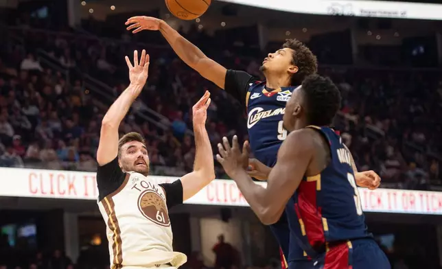 Golden State Warriors' Pat Spencer (61) shoots as Cleveland Cavaliers' Craig Porter Jr., rear, and Thomas Bryant defend during the first half of an NBA basketball game in Cleveland, Saturday, Dec. 6, 2025. (AP Photo/Phil Long)