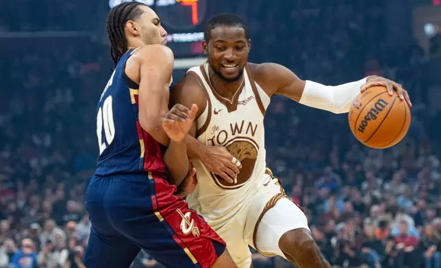 Golden State Warriors' Jonathan Kuminga, right, drives against Cleveland Cavaliers' Jaylon Tyson, during the first half of an NBA basketball game in Cleveland, Saturday, Dec. 6, 2025. (AP Photo/Phil Long)