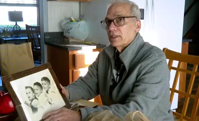 FILE - John Prevost, brother of new Pope Leo XIV, holds a portrait of the three Prevost brothers from 1958, Pope Leo, 3, left, John, 4, and Louis, 7, at his home, May 8, 2025, in New Lenox, Ill. (AP Photo/Obed Lamy, File)