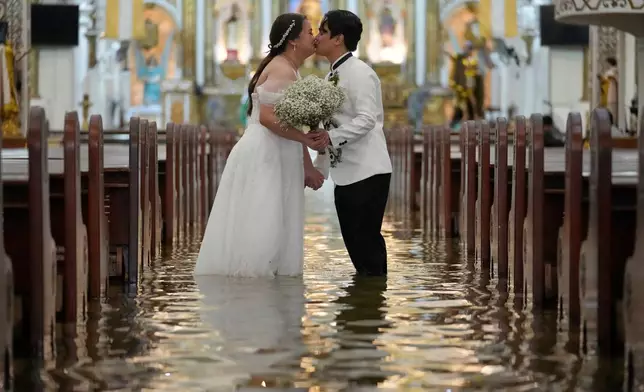 FILE - Newlyweds Jade Rick Verdillo, right, and Jamaica kiss during their wedding inside a flooded Barasoain church in Malolos, Philippines, July 22, 2025. (AP Photo/Aaron Favila, File)