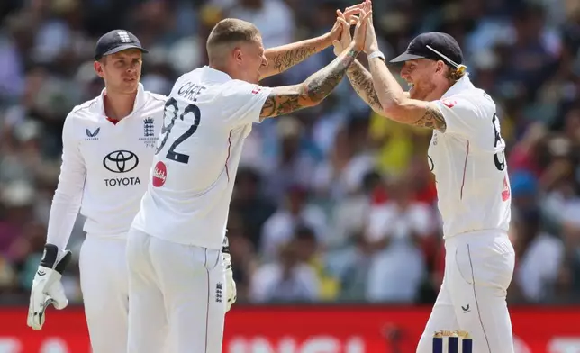 England's Brydon Carse, left, celebrates with Ben Stokes after dismissing Australia's Jake Weatherald, during play on day three of the third Ashes cricket test between England and Australia in Adelaide, Australia, Friday, Dec. 19, 2025. (AP Photo/James Elsby)