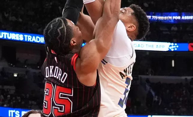 Milwaukee Bucks forward Giannis Antetokounmpo, right, drives to the basket against Chicago Bulls forward Isaac Okoro during the first half of an NBA basketball game in Chicago, Saturday, Dec. 27, 2025. (AP Photo/Nam Y. Huh)