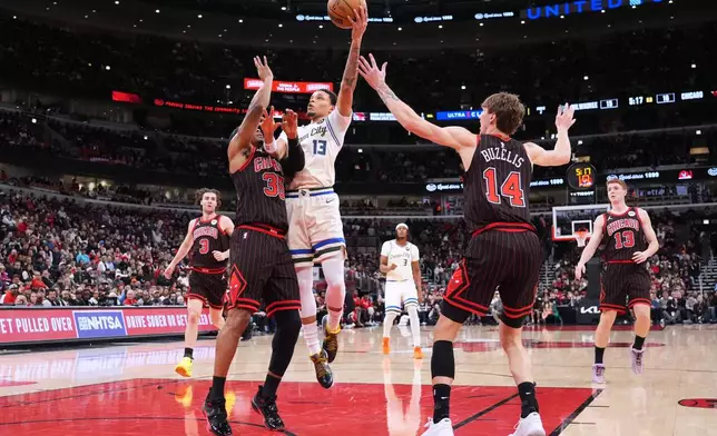 Milwaukee Bucks guard Ryan Rollins (13) drives to the basket against Chicago Bulls forward Isaac Okoro, left, and forward Matas Buzelis during the first half of an NBA basketball game in Chicago, Saturday, Dec. 27, 2025. (AP Photo/Nam Y. Huh)