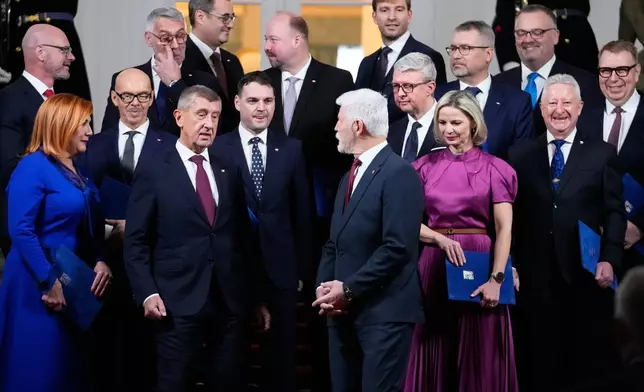 Czech Republic's President Petr Pavel, center, and Prime Minister Andrej Babis, center left, pose for a family photo with newly appointed government members at the Prague Castle in Prague, Czech Republic, Monday, Dec. 15, 2025. (AP Photo/Petr David Josek)