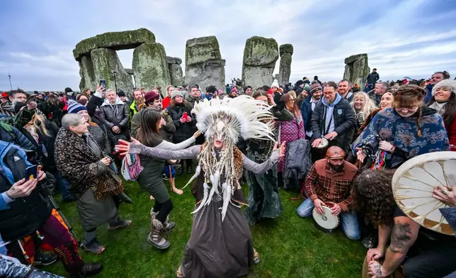 Kefan Wang, a shaman from China and Abbie Coombs from London dancing as people celebrate the Winter Solstice sunrise celebrations at Stonehenge, a world-famous prehistoric monument on Salisbury Plain, England, Sunday, Dec. 21, 2025. (AP Photo/Anthony Upton)