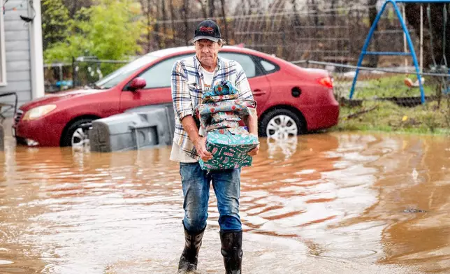 Steve Wogoman carries Christmas presents from his daughter-in-law's flooded home following heavy rains on Monday, Dec. 22, 2025, in Redding, Calif. (AP Photo/Noah Berger)
