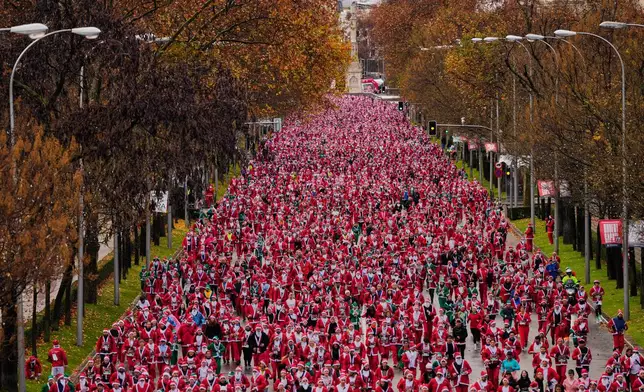 People dressed in Santa Claus costumes take part in a morning run in Madrid, Spain, on Sunday, Dec. 21, 2025, during the annual Santa race through the streets of the Spanish capital. (AP Photo/Manu Fernandez)