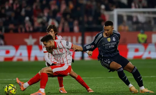 Girona's Ivan Martin, left, fights for the ball with Real Madrid's Kylian Mbappe during a Spanish La Liga soccer match between Girona and Real Madrid, in Girona, Spain, Sunday, Nov. 30, 2025. (AP Photo/Joan Monfort)