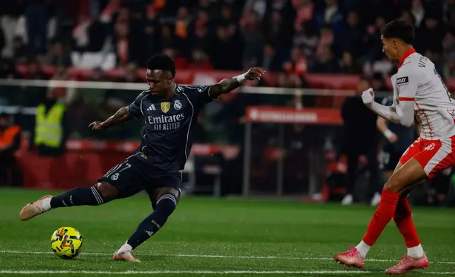 Real Madrid's Vinicius Junior, left, tries a shot during a Spanish La Liga soccer match between Girona and Real Madrid, in Girona, Spain, Sunday, Nov. 30, 2025. (AP Photo/Joan Monfort)