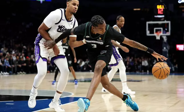 Minnesota Timberwolves forward Jaden McDaniels, front right, controls the ball as Sacramento Kings forward Keegan Murray, left, defends during the first half of an NBA basketball game Sunday, Dec. 14, 2025, in Minneapolis. (AP Photo/Matt Krohn)
