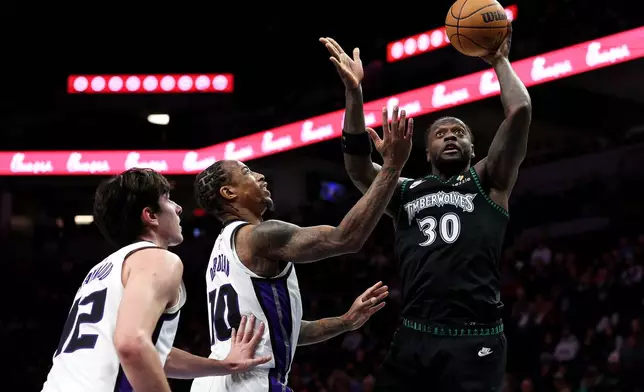 Minnesota Timberwolves forward Julius Randle, right, goes up for a shot as Sacramento Kings guard Demar Derozan, middle, defends during the first half of an NBA basketball game Sunday, Dec. 14, 2025, in Minneapolis. (AP Photo/Matt Krohn)