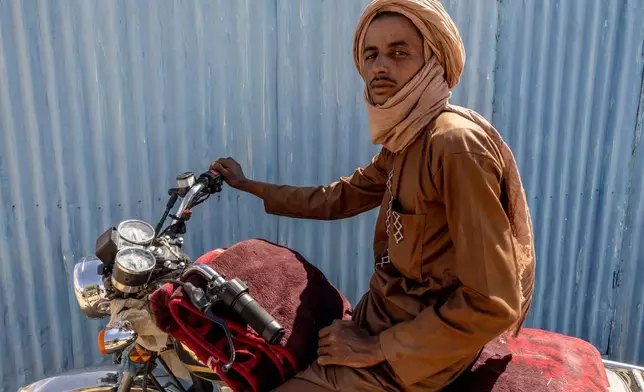 A man, whose shop was destroyed when Africa Corps burned his village in the Mopti region of Mali, poses on his motorcycle in Douankara, Hodh El Chargui Region, Mauritania, Nov. 7, 2025. (AP Photo/Caitlin Kelly)