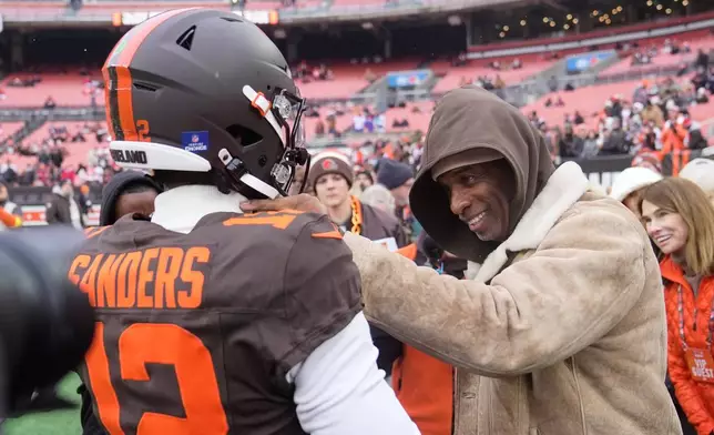Cleveland Browns quarterback Shedeur Sanders (12) visits with his father Deion Sanders, right, during warmups before an NFL football game against the Tennessee Titans in Cleveland, Sunday, Dec. 7, 2025. (AP Photo/Sue Ogrocki)