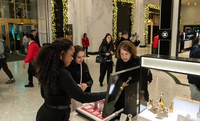 Associated Press reporter Anne D'Innocenzio helps a customer out at Macy's flagship store, Friday, Nov. 21, 2025, in New York. (AP Photo/Yuki Iwamura)