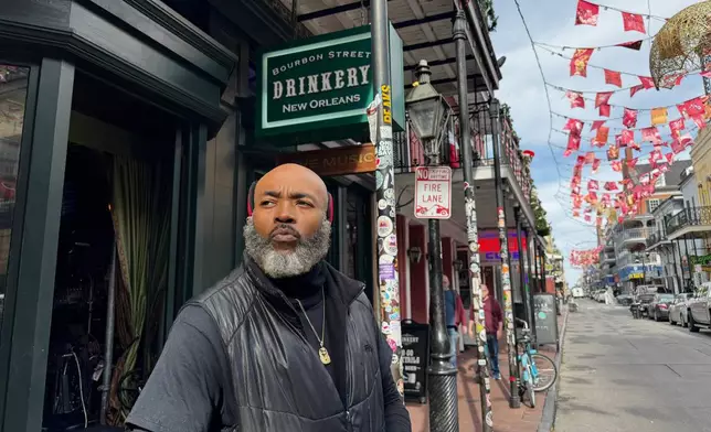Miguel Thornton stands under memorial flags for the victims of a Jan. 1, 2025, vehicle ramming attack, outside of the Bourbon Street bar, where he works, on Monday, Dec. 29, 2025, in New Orleans. (AP Photo/Jack Brook)
