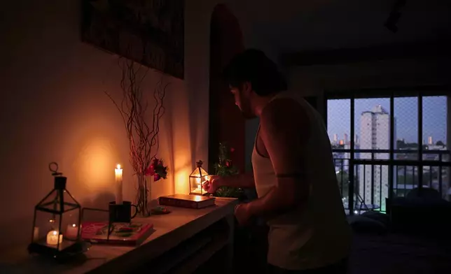 Gustavo Stancial lights a candle in his home during a blackout in Sao Paulo, Thursday, Dec. 11, 2025. (AP Photo/Ettore Chiereguini)