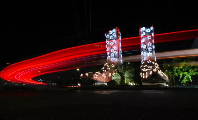 In a timed exposure, vehicles pass a pair of cowboys boots standing 40 feet tall and 30 feet long that have been decorated with lights for the holidays, Tuesday, Dec. 9, 2025, in San Antonio. (AP Photo/Eric Gay)