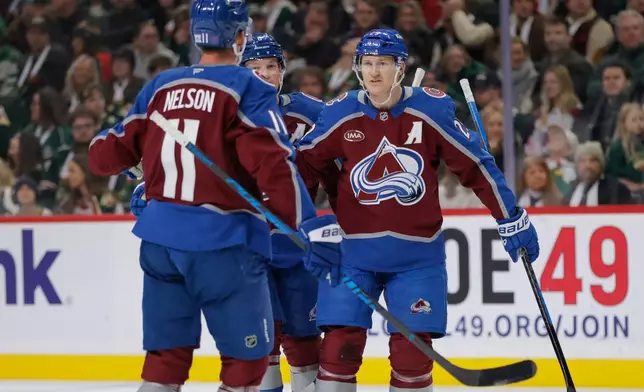 Colorado Avalanche center Nathan MacKinnon celebrates with defenseman Cale Makar and center Brock Nelson (11) after scoring during the second period of an NHL hockey game against the Minnesota Wild, Sunday, Dec. 21, 2025, in St. Paul, Minn. (AP Photo/Bailey Hillesheim)