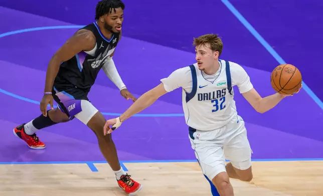 Dallas Mavericks forward Cooper Flagg, right, looks to pass the ball while guarded by Utah Jazz guard Isaiah Collier, left, during the first half of an NBA basketball game, Monday, Dec. 15, 2025, in Salt Lake City. (AP Photo/Tyler Tate)