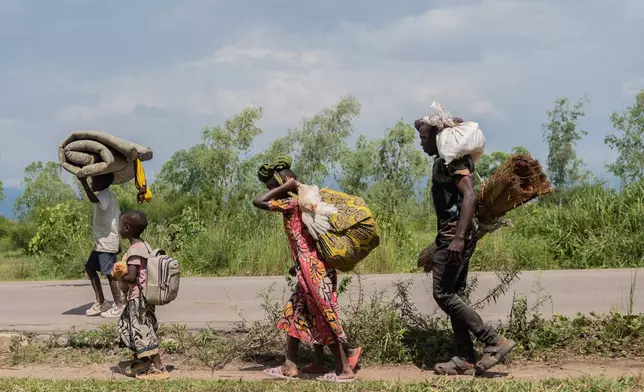 Displaced people who fled the war between FARDC and M23 rebels walk with their belongings as they return to their homes in Luvungi, Democratic Republic of Congo, Saturday, Dec. 13, 2025. (AP Photo/Moses Sawasawa)