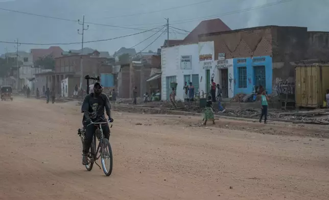A man rides a bicycle along a street as people return to homes in Uvira Democratic Republic of Congo, Saturday, Dec. 13, 2025. (AP Photo/Moses Sawasawa)