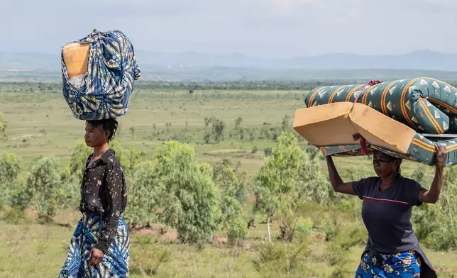 Displaced people who fled the war between FARDC and M23 rebels walk with their belongings as they return to their homes in Luvungi, Democratic Republic of Congo, Saturday, Dec. 13, 2025. (AP Photo/Moses Sawasawa)