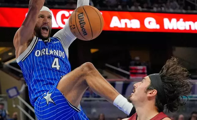 Orlando Magic guard Jalen Suggs (4) dunks over Miami Heat guard Jaime Jaquez Jr. (11) during the second half of an NBA basketball game, Friday, Dec. 5, 2025, in Orlando, Fla. (AP Photo/John Raoux)