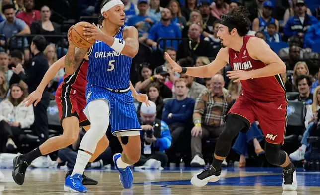 Orlando Magic forward Paolo Banchero (5) passes the ball as Miami Heat guard Jaime Jaquez Jr. defends during the first half of an NBA basketball game, Friday, Dec. 5, 2025, in Orlando, Fla. (AP Photo/John Raoux)