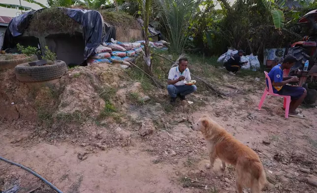 Village security volunteers eat dinner outside a shelter during Thai and Cambodian soldiers clashes in Surin province, Thailand, Tuesday, Dec. 9, 2025. (AP Photo/Sakchai Lalit)