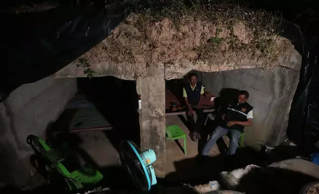 Village security volunteers sit inside shelter during Thai and Cambodian soldiers clashes in Surin province, Thailand, Tuesday, Dec. 9, 2025. (AP Photo/Sakchai Lalit)