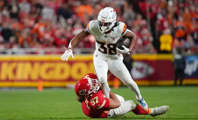Denver Broncos running back Jaleel McLaughlin (38) rushes for a first down as Kansas City Chiefs defensive end Ashton Gillotte (97) tries to stop him during the first half of an NFL football game Thursday, Dec. 25, 2025, in Kansas City, Mo. (AP Photo/Ed Zurga)