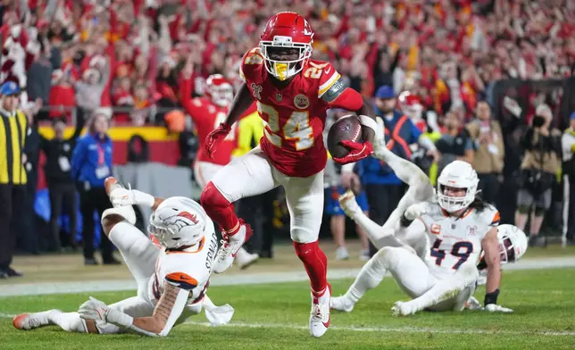 Kansas City Chiefs running back Brashard Smith, center, evades tackles by Denver Broncos linebacker Justin Strnad, left, and linebacker Alex Singleton (49) while scoring a touchdown during the first half of an NFL football game Thursday, Dec. 25, 2025, in Kansas City, Mo. (AP Photo/Ed Zurga)